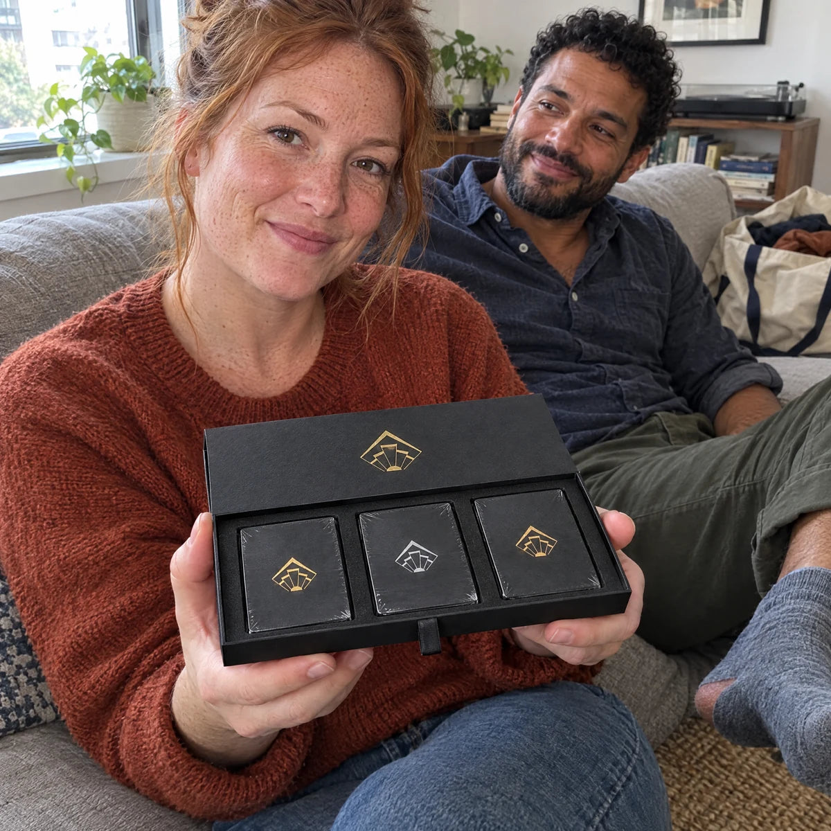 Couple on a sofa showing the open Twosome Cards box and its three decks.