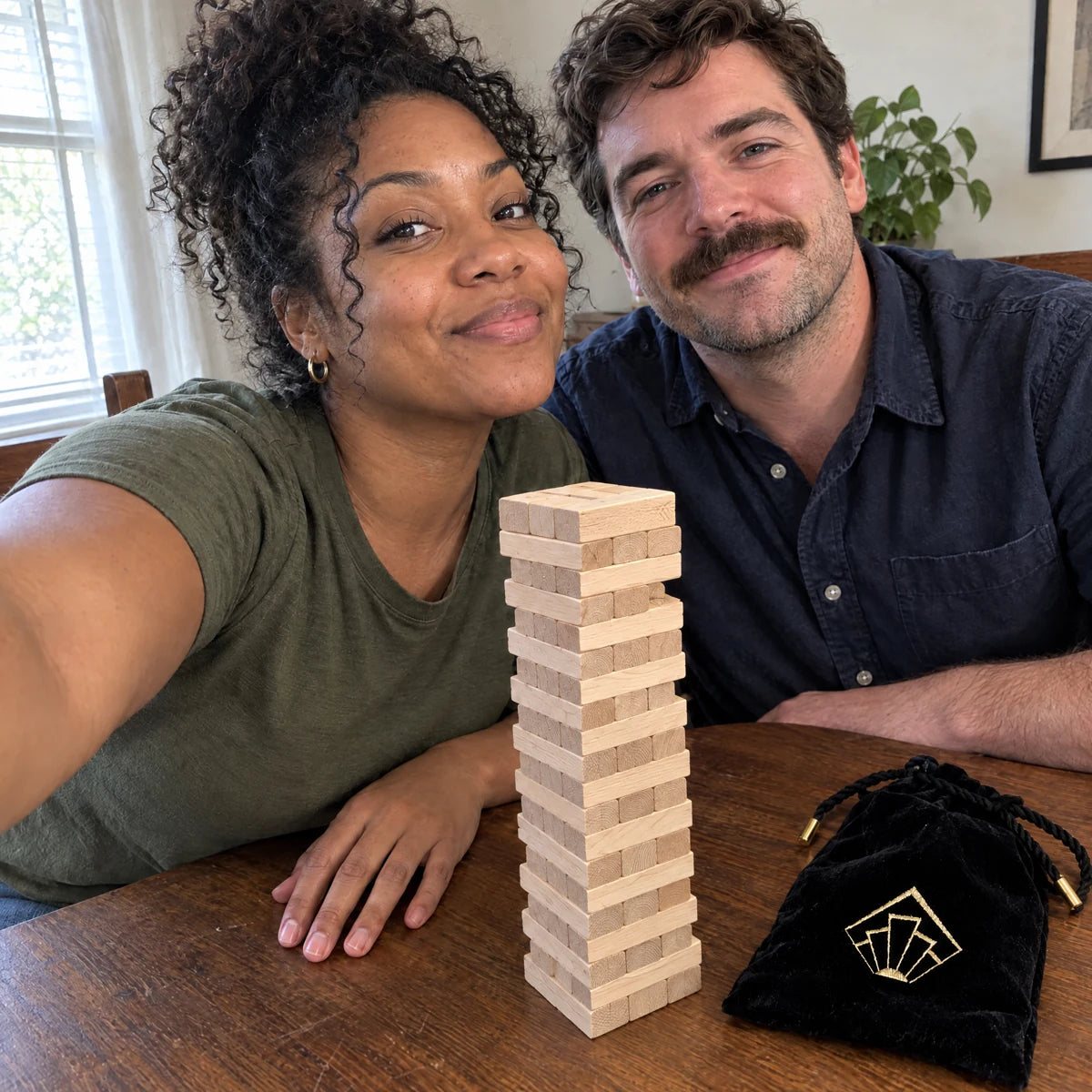 Couple taking a selfie beside the Tease Tower and black drawstring pouch.
