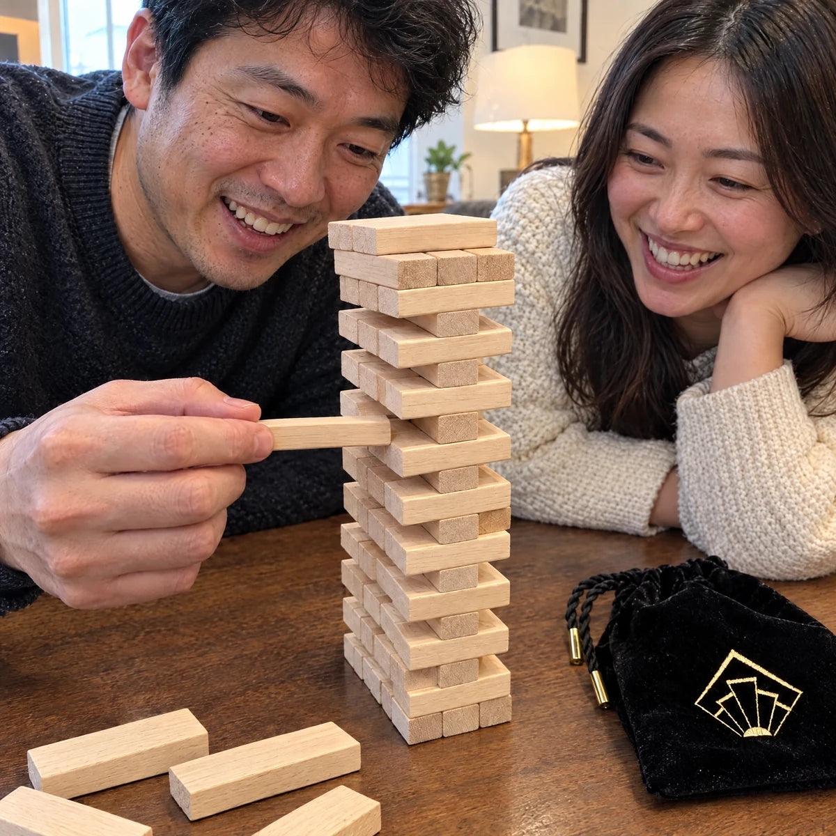 Couple carefully sliding a wooden block from the Tease Tower.