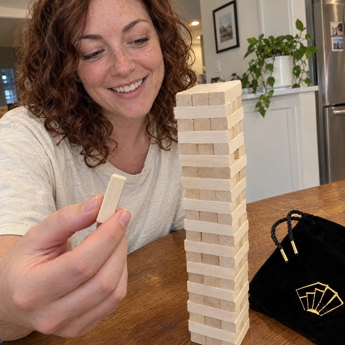 Woman holding a wooden block beside the Tease Tower at her kitchen table.